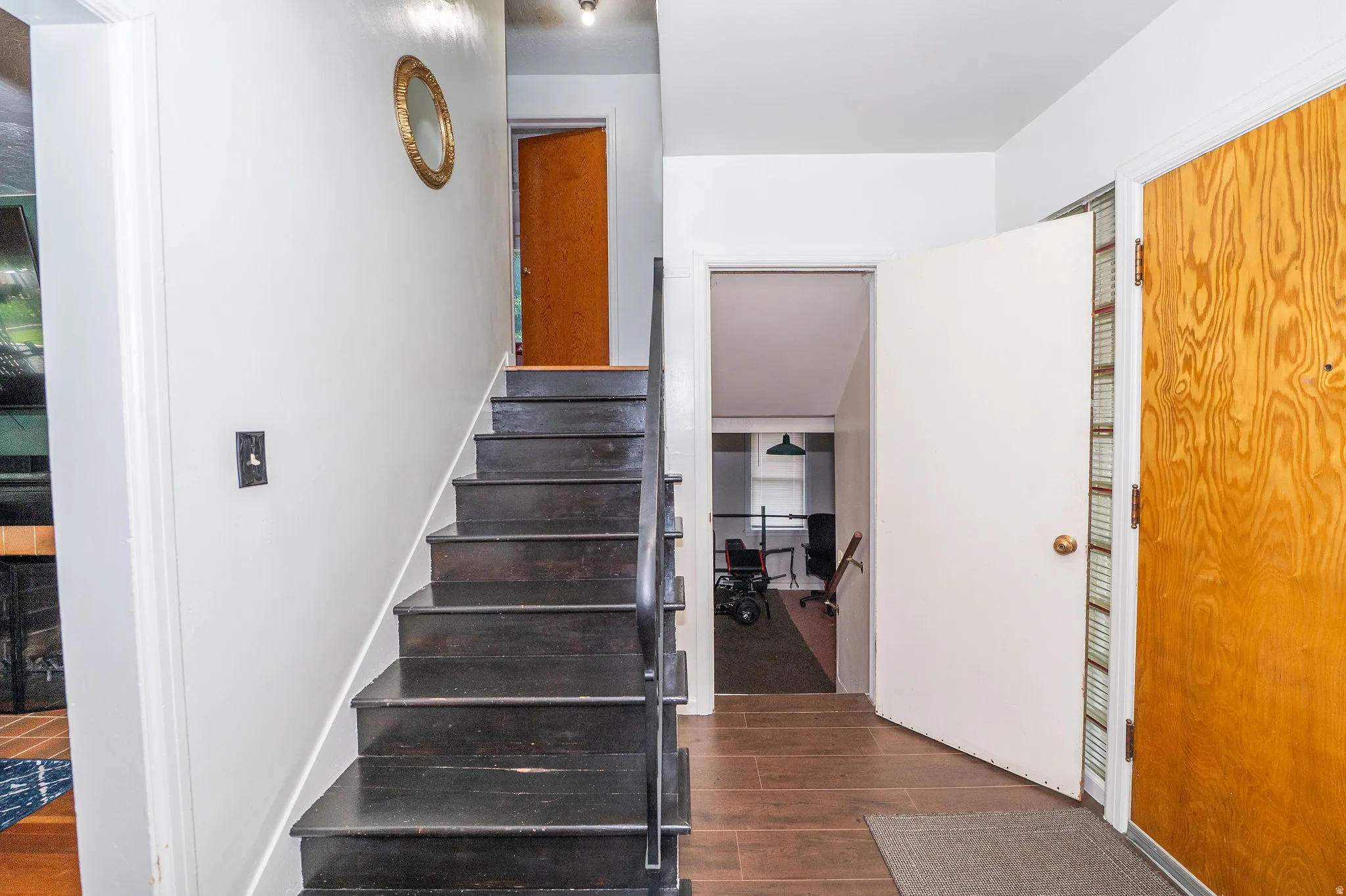 Entryway featuring dark wood-finish stairs with a black metal handrail