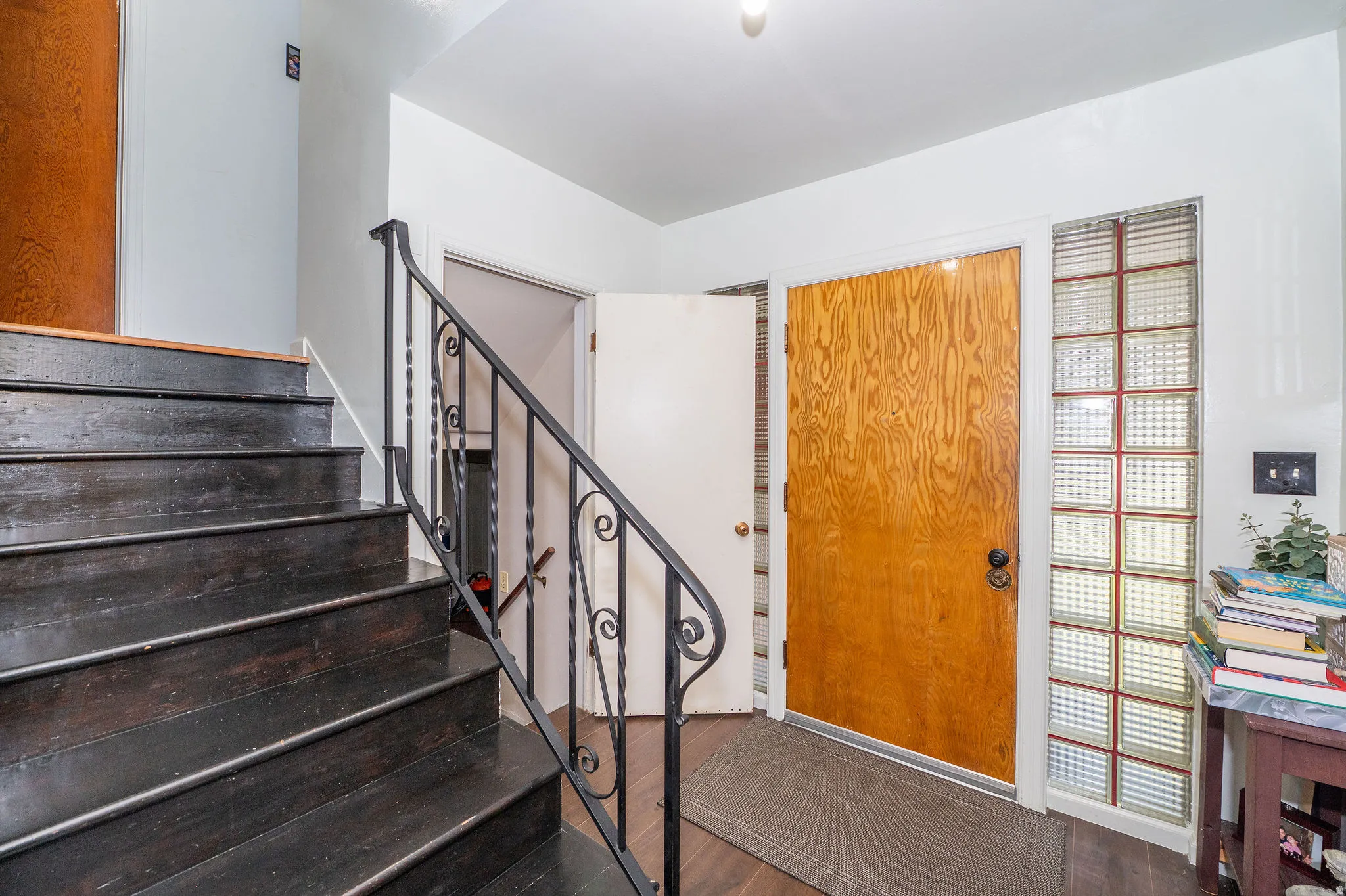 Entryway featuring wood-finish flooring, a wood-panel door, and a decorative glass block sidelight