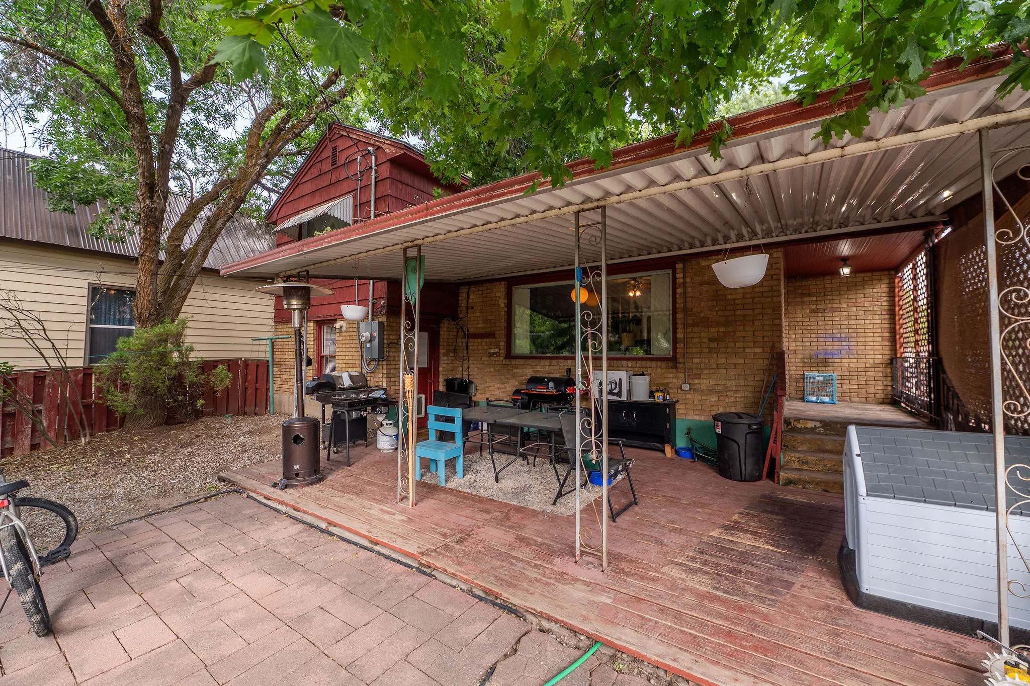 Covered patio area featuring a corrugated roof, wood-finish flooring, and brick wall accents