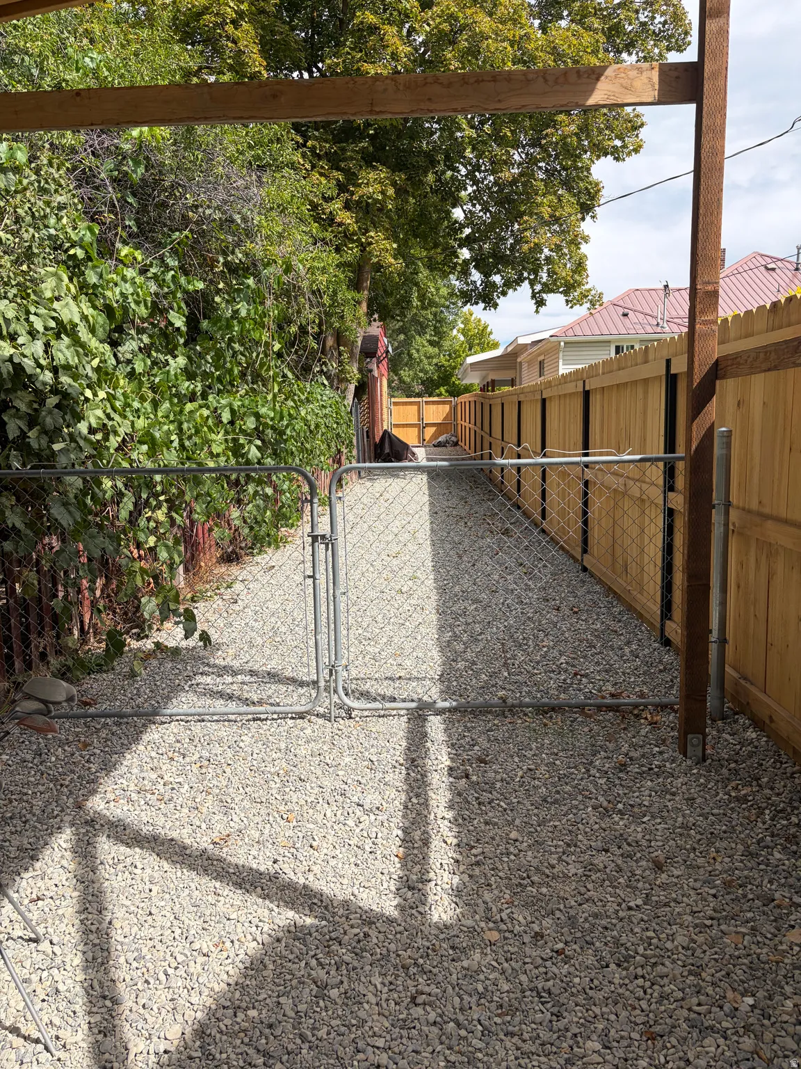 Gravel pathway featuring a chain-link gate and wood privacy fencing