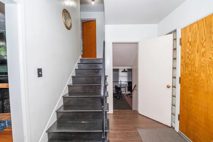 Entryway featuring dark wood-finish stairs with a black metal handrail