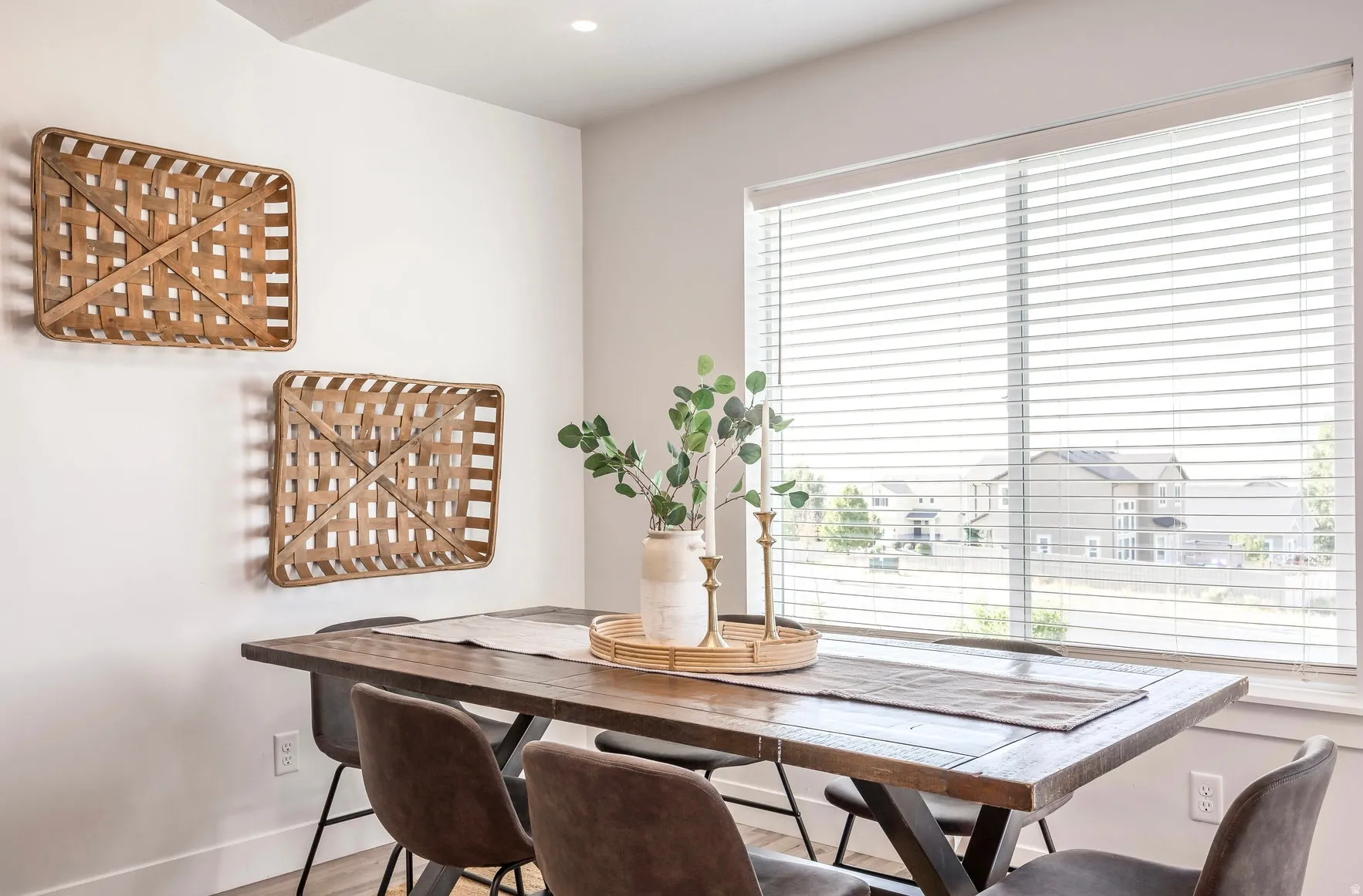 Dining area featuring a large window with white horizontal blinds, wood-finish flooring, and white baseboards