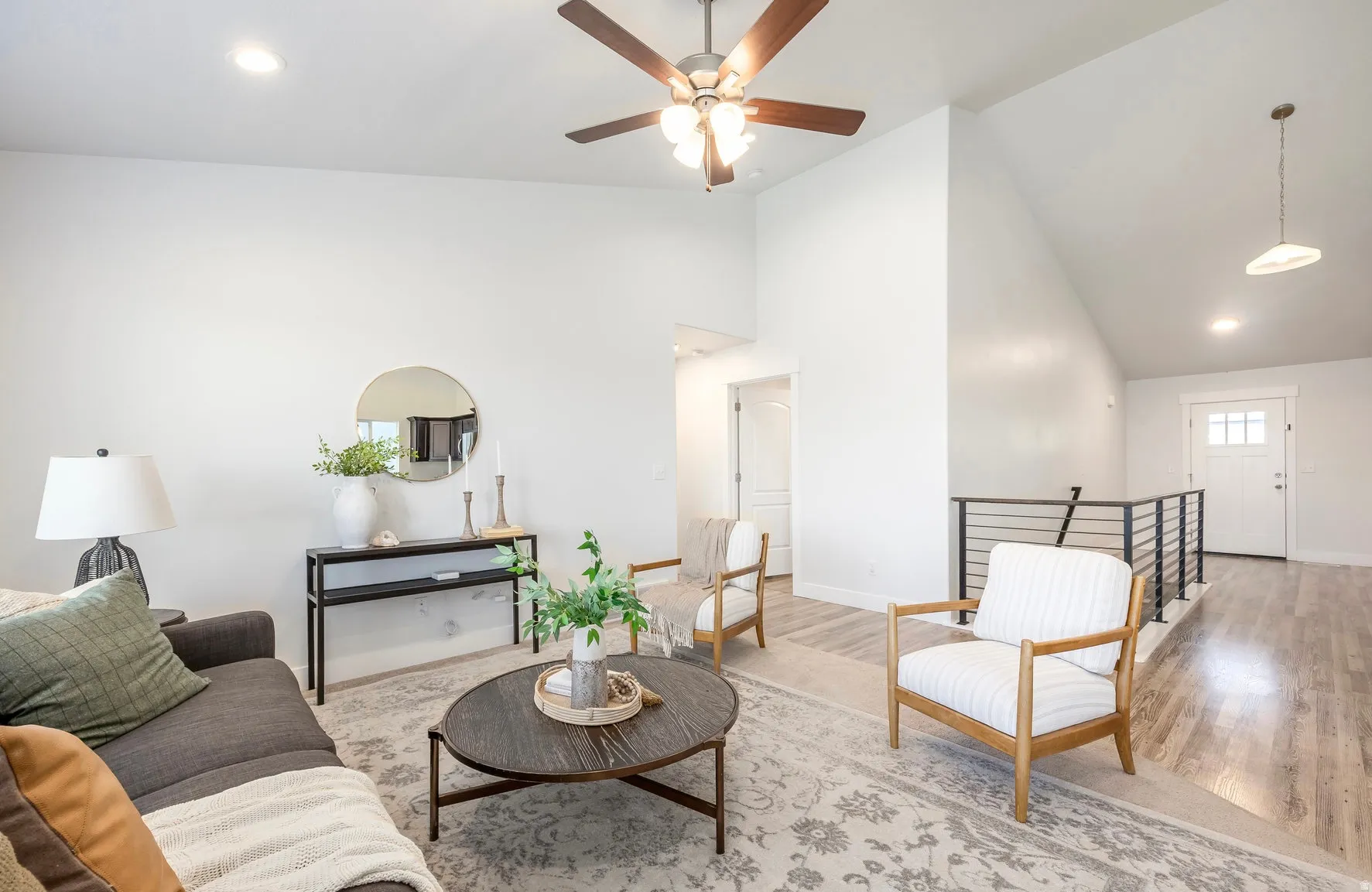 Vaulted ceiling living room featuring a ceiling fan with integrated lighting, recessed lighting, and light wood-finish flooring