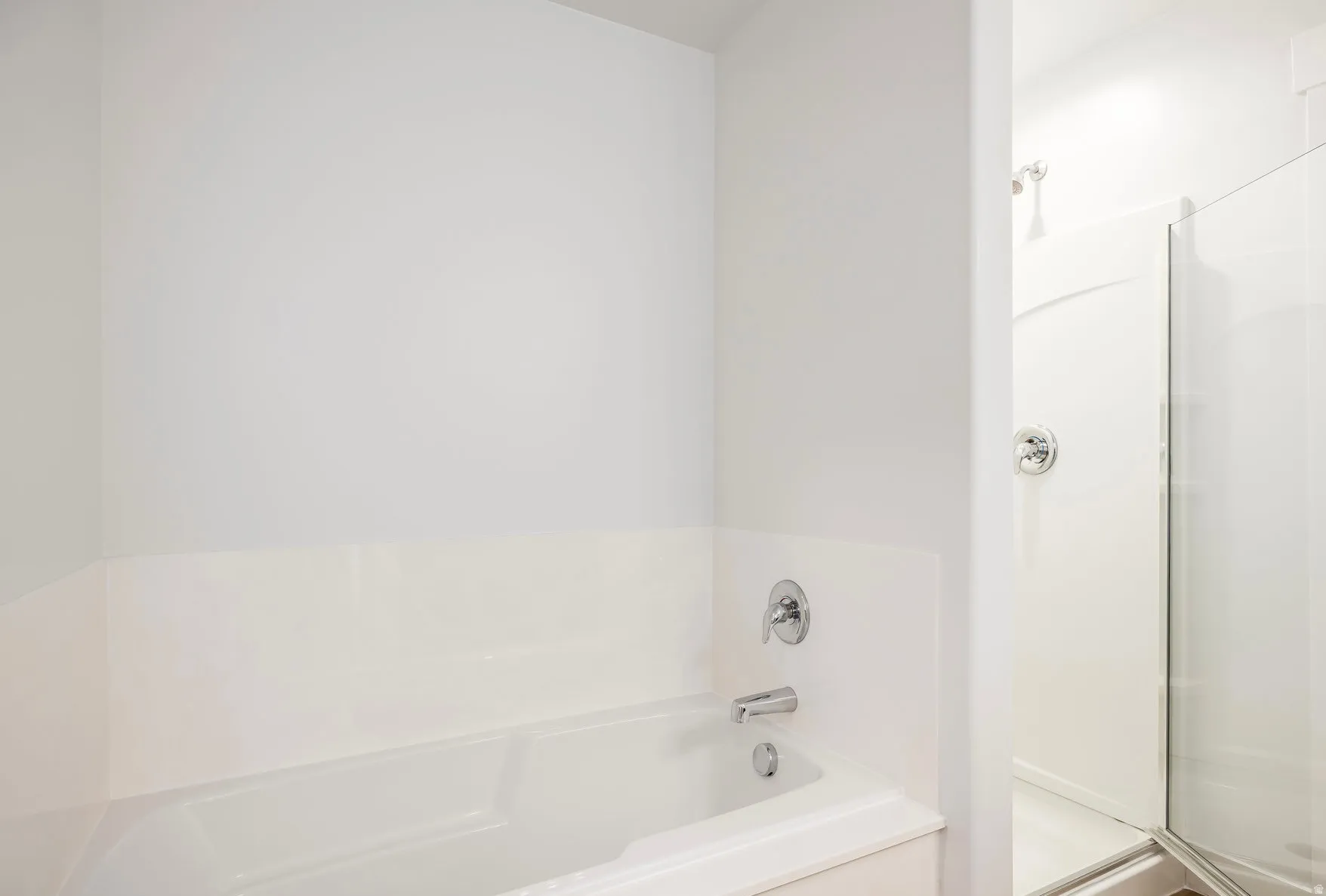 White soaking tub with chrome fixtures and surrounding white tile-effect wall paneling