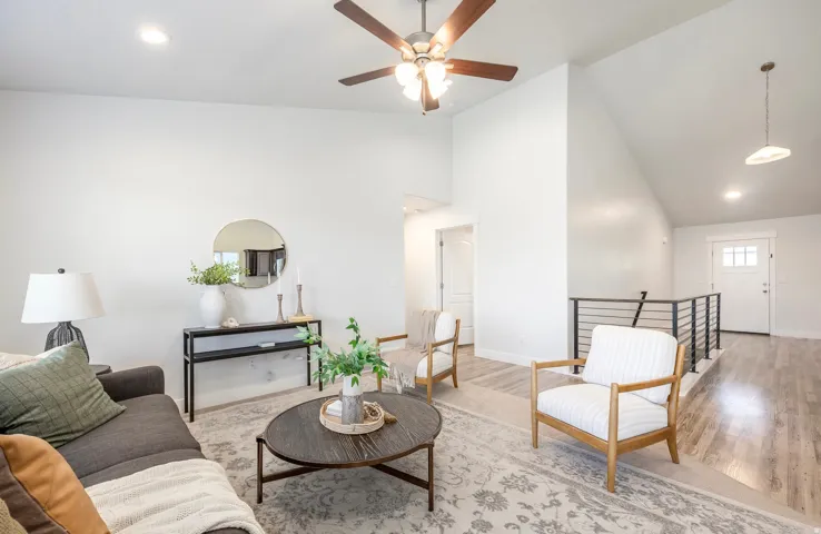 Vaulted ceiling living room featuring a ceiling fan with integrated lighting, recessed lighting, and light wood-finish flooring
