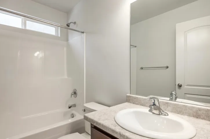 Bathroom featuring a white tub-shower combination, a vanity with an oval undermount sink, a chrome faucet, and a large wall-mounted mirror