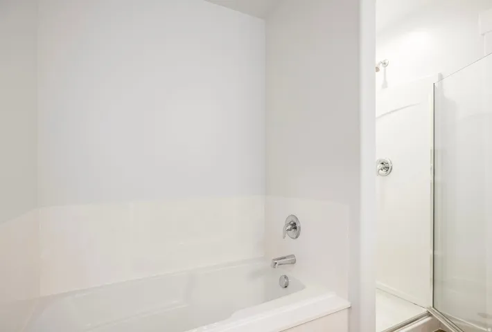 White soaking tub with chrome fixtures and surrounding white tile-effect wall paneling