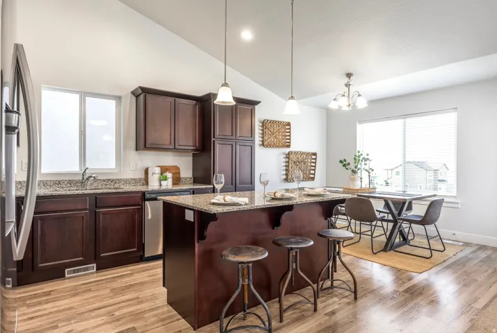 Kitchen featuring wood-finish flooring, dark wood cabinetry, granite countertops, and stainless steel appliances