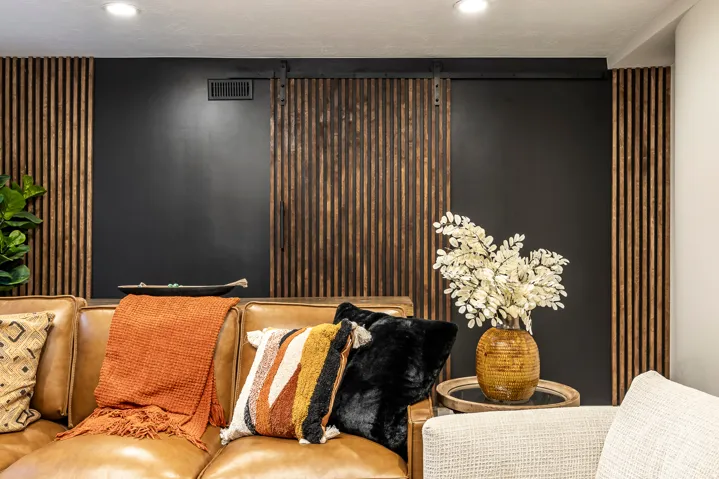 Accent wall featuring dark paint and vertical wood slat paneling with a barn door