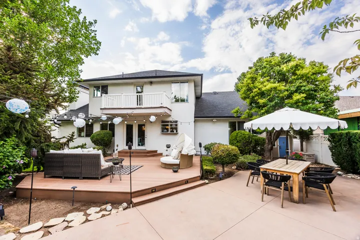 Multi-level rear exterior featuring a composite deck, a concrete patio, and mature trees