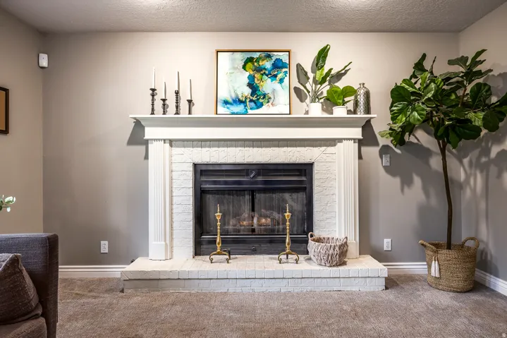 Fireplace featuring a white painted brick surround, a contrasting black firebox, a substantial white mantel, and traditional white baseboards