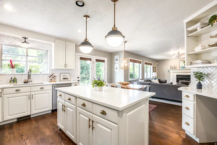 Kitchen featuring a large island with white cabinetry and a light-toned countertop, dark wood-finish flooring, and white subway tile backsplash in a herringbone pattern