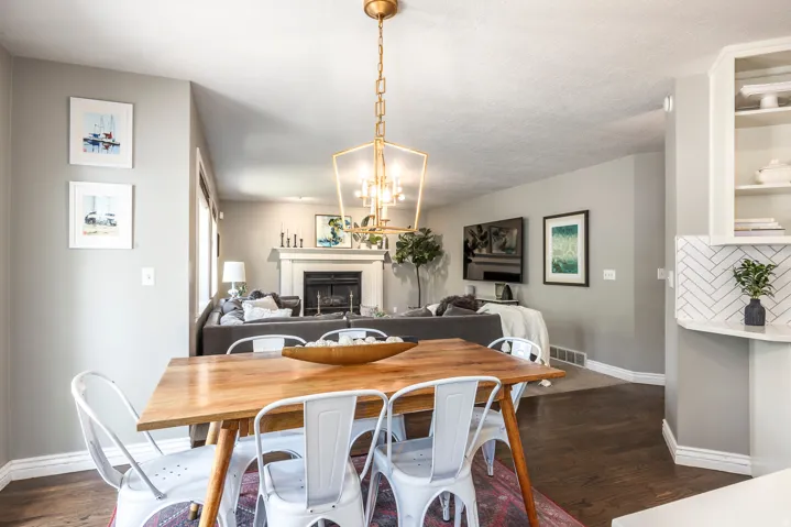 Dining area featuring wood-finish flooring, a contemporary chandelier, and an open layout to a living room with a fireplace