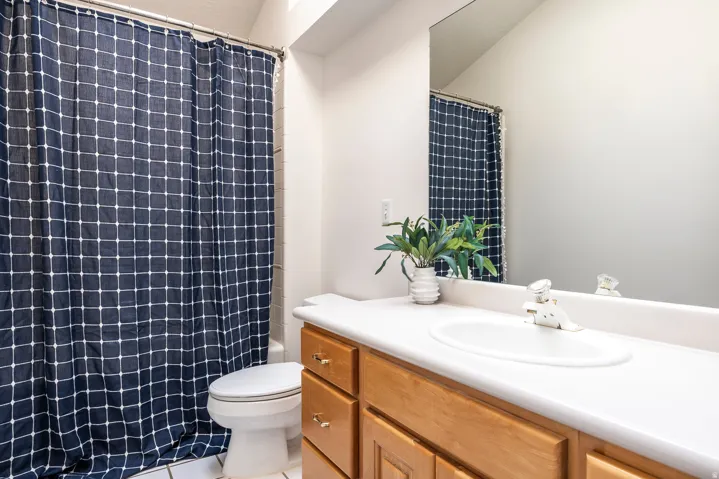 Bathroom featuring a wood-finish vanity with a built-in sink, white countertop, and a large wall-mounted mirror