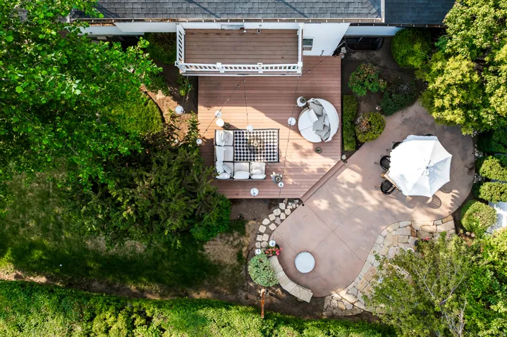 Expansive outdoor living area featuring a multi-level wood-finish deck and an irregularly shaped concrete patio