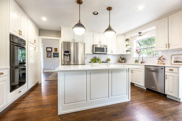 Bright kitchen featuring white cabinetry, a central island with a solid surface countertop, stainless steel appliances, and wood-finish flooring