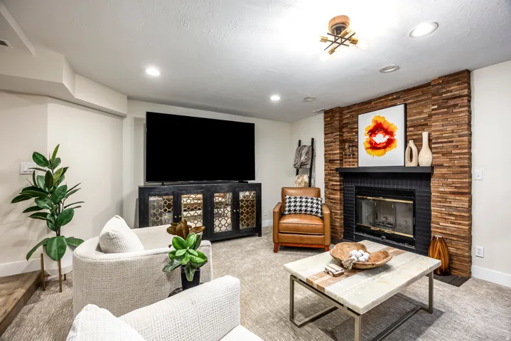 Living area featuring a floor-to-ceiling stacked wood accent wall surrounding a fireplace with a black mantel and hearth