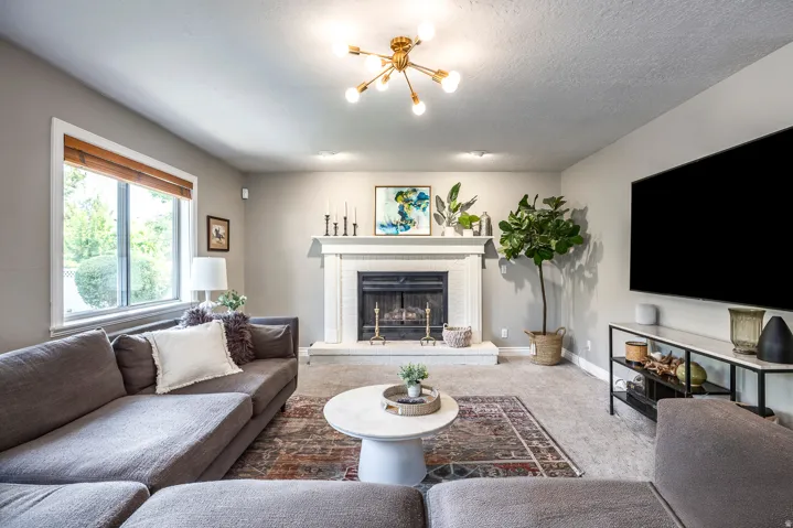 Living area featuring a white fireplace with a mantel, recessed lighting, and a modern gold-finish ceiling fixture