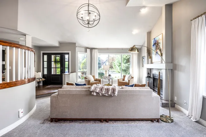 Living area featuring a fireplace with a white mantel, large windows, a built-in entry bench, a dark wood-paneled front door, and a curved wooden banister