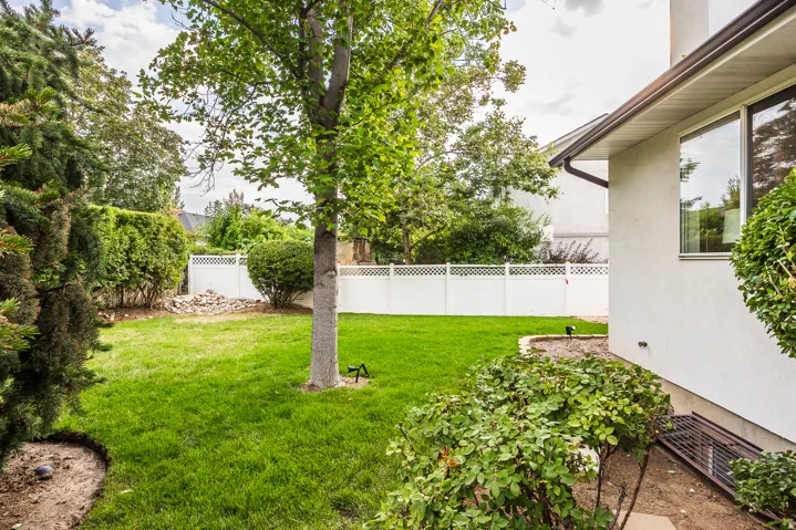 Expansive backyard featuring a manicured lawn and mature trees