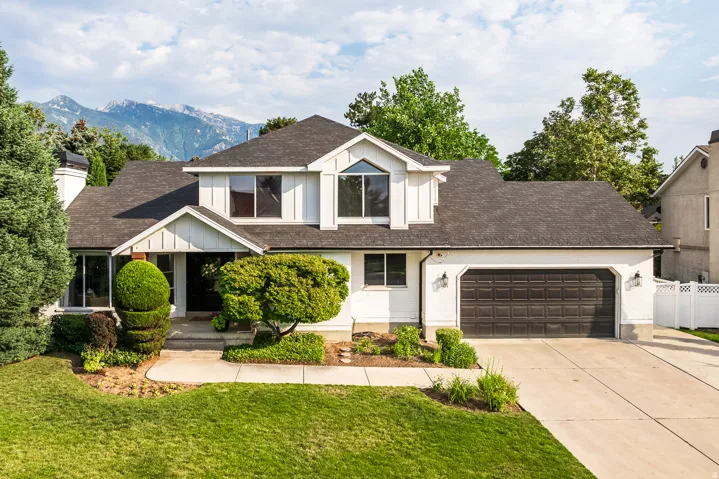 White exterior residence featuring a dark asphalt shingle roof and a two-car garage