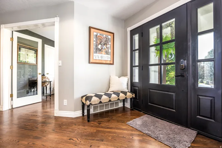 Hardwood flooring extends throughout this entryway featuring a black front door with glass panels and a coordinating sidelight