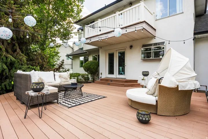 Expansive exterior deck featuring a second-story balcony with white railings, a double-door entry, a stepped approach, and a stucco exterior