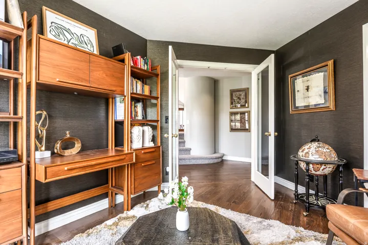 Interior space featuring dark textured wall coverings, wood-finish flooring, and white trim