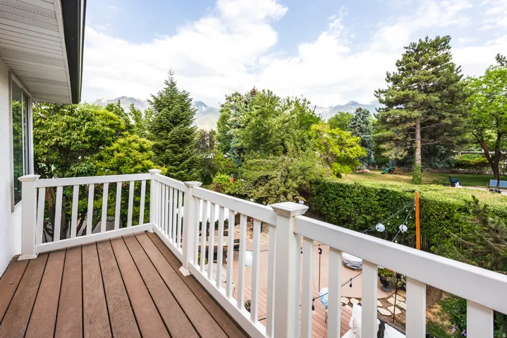 Balcony featuring wood-finish decking, white railing, and exterior siding