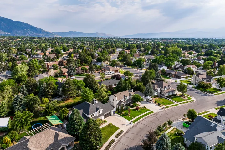 Residential neighborhood with mature trees, established landscaping, and mountain backdrop