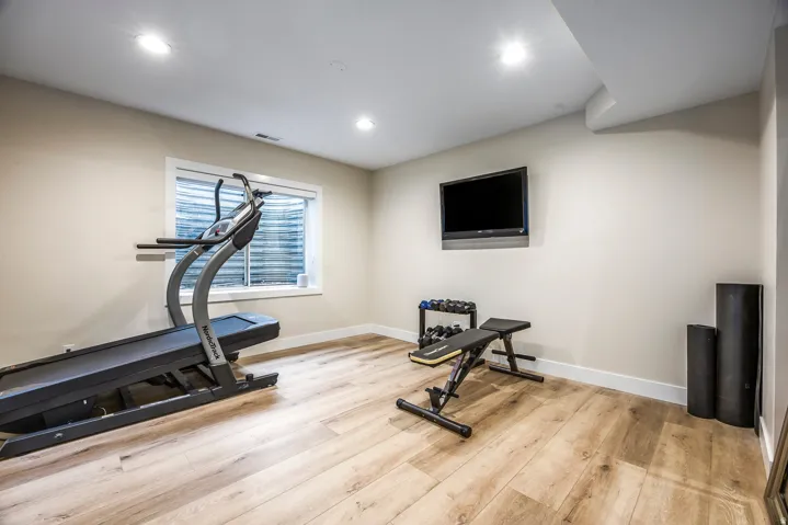 Spacious room featuring wood-finish flooring, recessed lighting, and a wall-mounted display