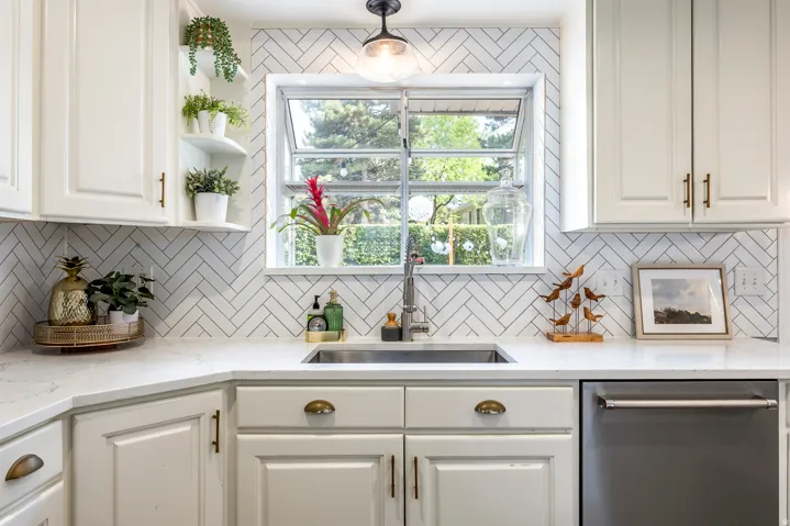Kitchen with white cabinetry, a stainless steel sink, and light-toned countertops