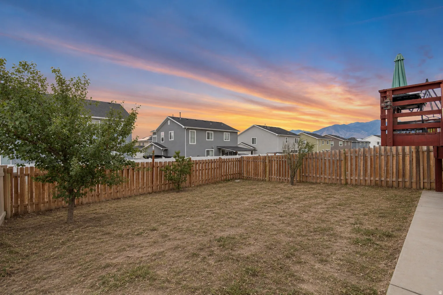 Expansive backyard with wood privacy fencing, mature trees, and a concrete patio