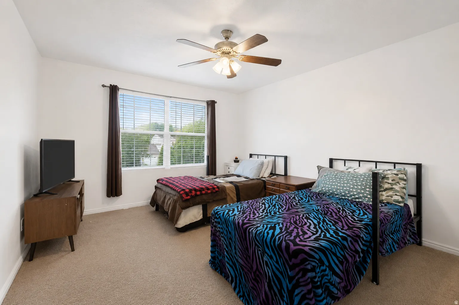 Carpeted room featuring a ceiling fan with integrated lighting, a double window with blinds, and white walls