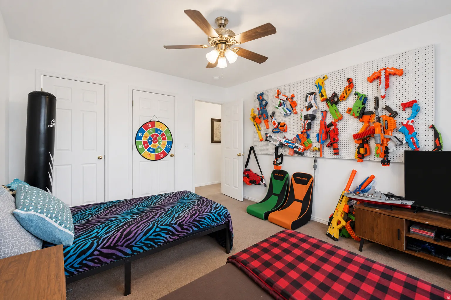 Bright room featuring a ceiling fan with light fixture, carpeted flooring, and two white paneled doors