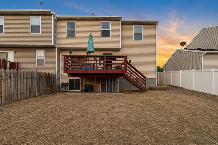 Spacious backyard featuring a multi-level deck with stairs, a sliding glass door for outdoor access, and a wood privacy fence