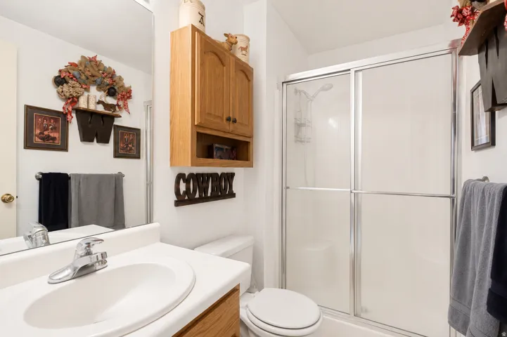 White bathroom featuring a single vanity with an integrated sink, polished chrome faucet, and a large wall-mounted mirror