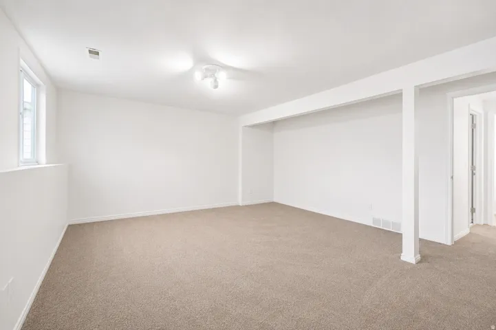 Carpeted room with white walls, a recessed window, and white trim