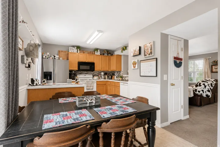 Kitchen and dining area featuring light wood cabinetry, stainless steel appliances, and a tile floor