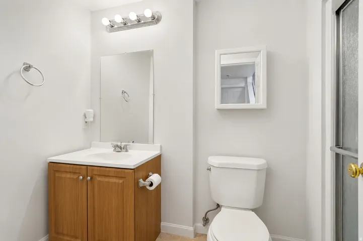 Bathroom featuring a wood-finish vanity with a white countertop and integrated sink, chrome faucet, and a wall-mounted mirror