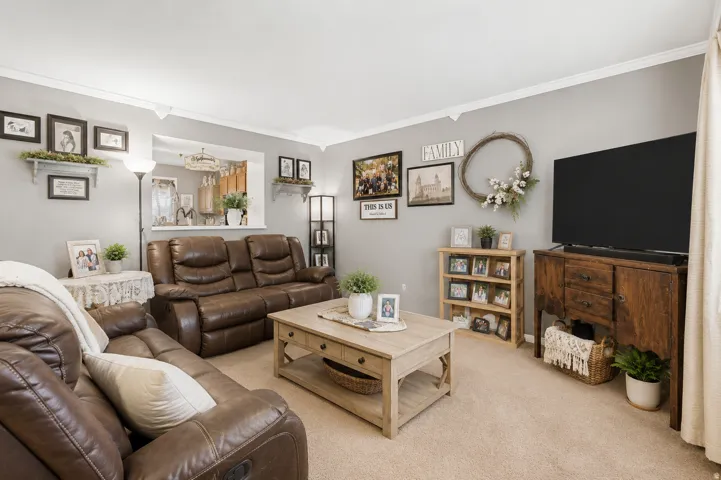 Living area featuring light beige carpeting, light gray wall paint, and white crown molding