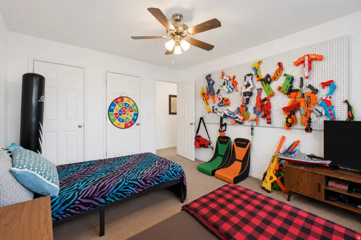 Bright room featuring a ceiling fan with light fixture, carpeted flooring, and two white paneled doors