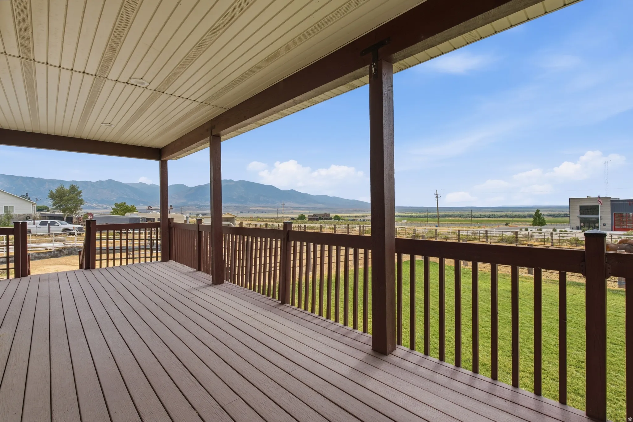 Covered porch featuring wood-finish decking, brown railing, and a slatted ceiling