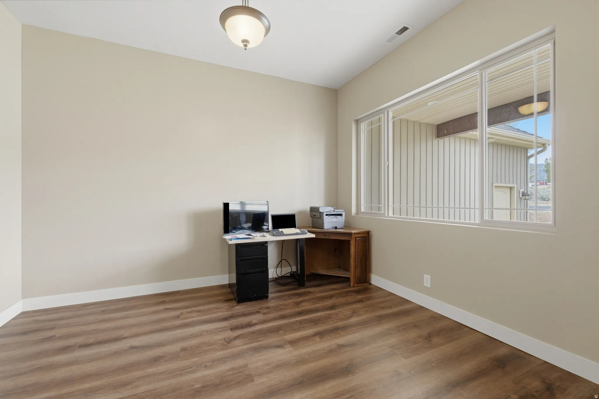 Interior room featuring wood-finish flooring, neutral wall tones, and white baseboards