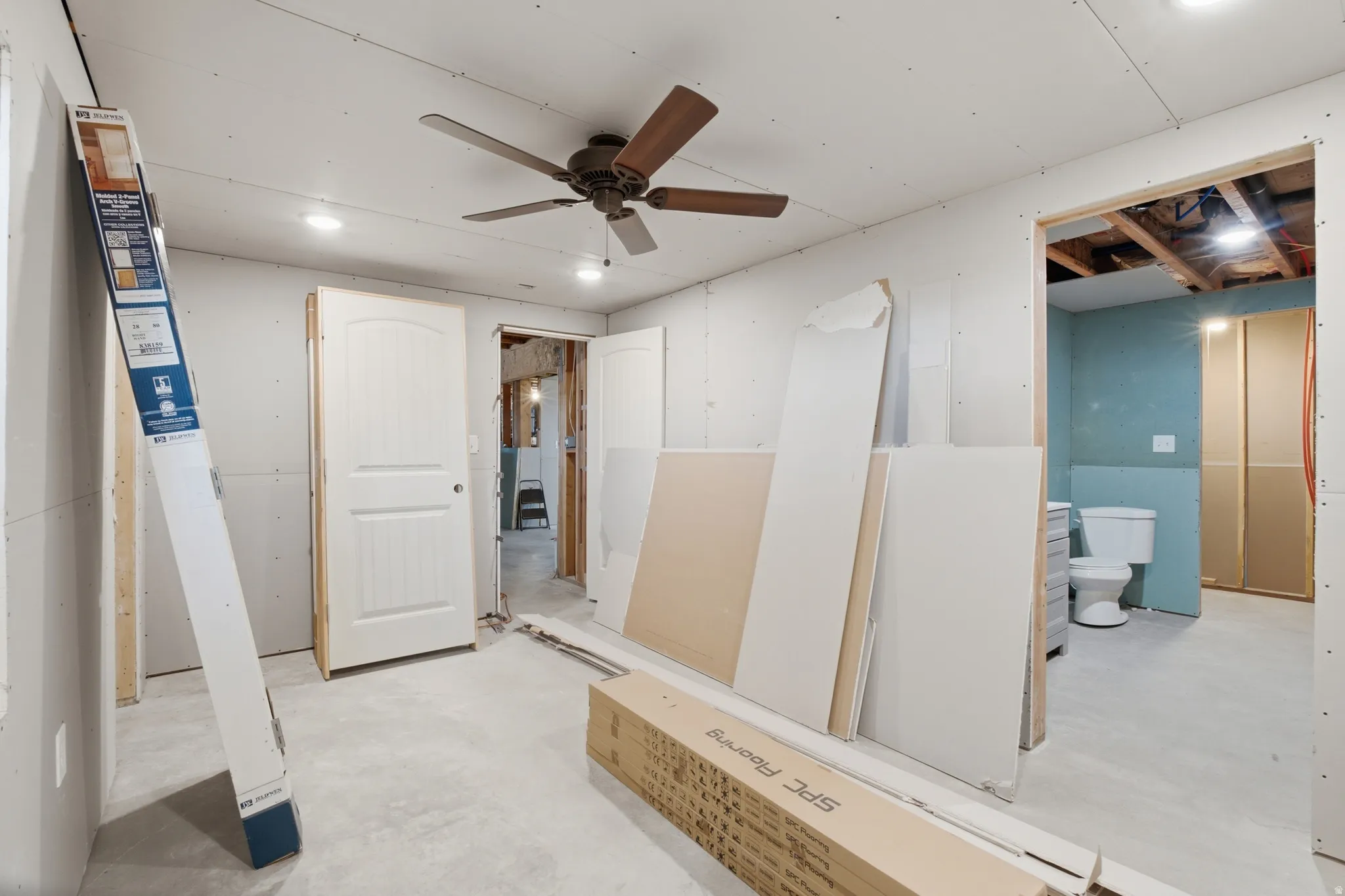 Unfinished room featuring a ceiling fan with light, recessed lighting, and a white interior door