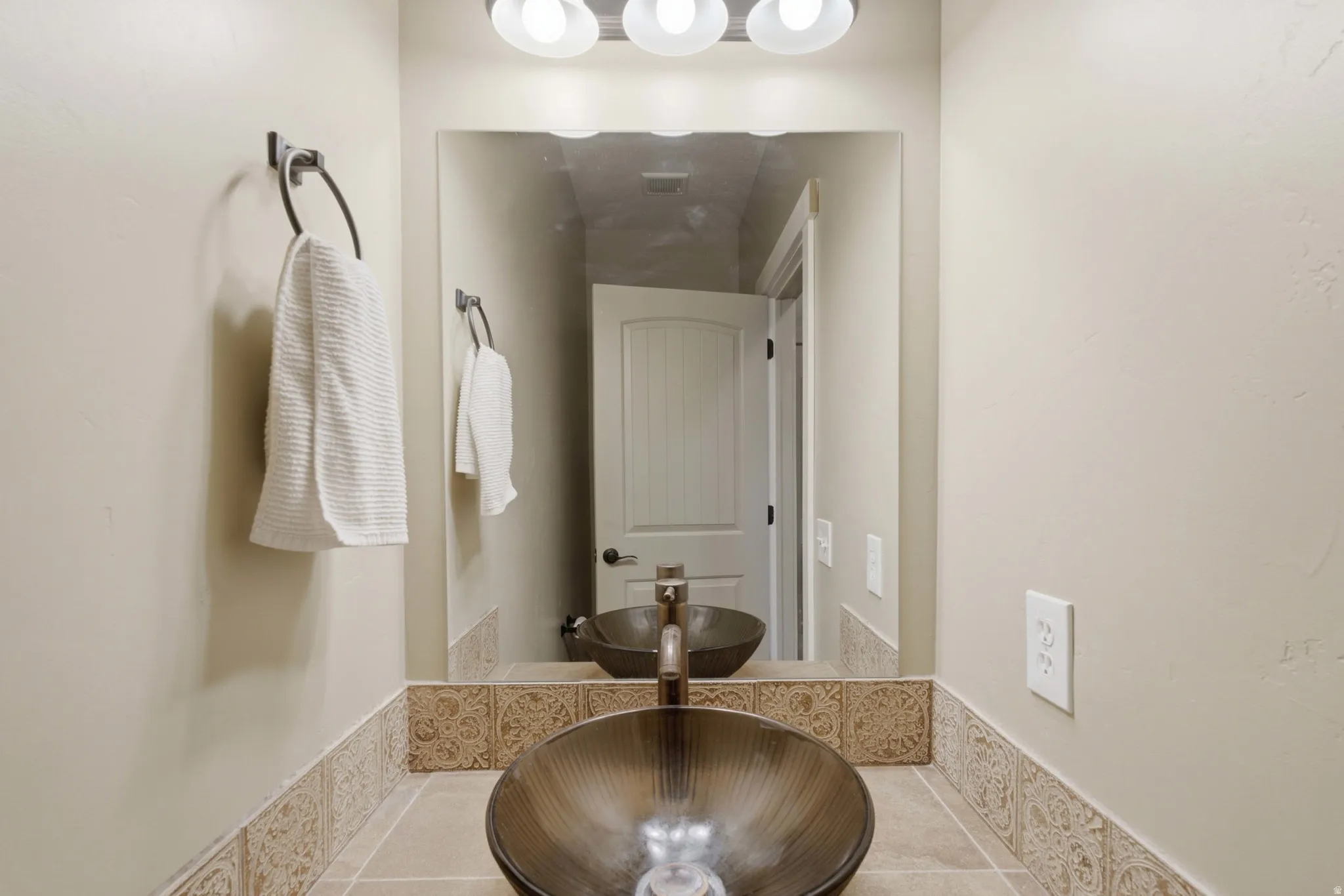 Bathroom vanity featuring a vessel sink, dark bronze faucet, and a large mirror
