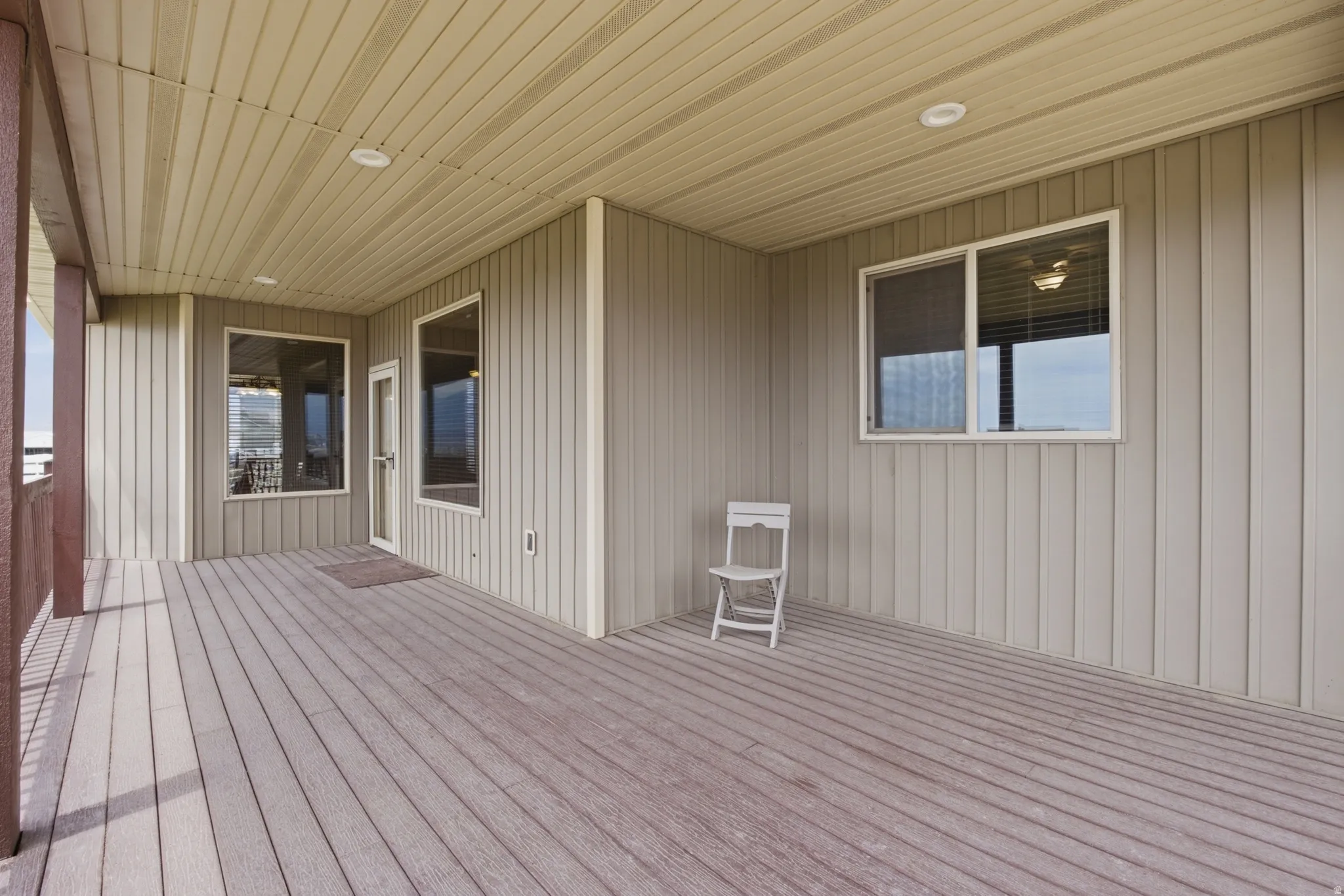 Covered outdoor deck with composite decking, recessed lighting, and vertical siding