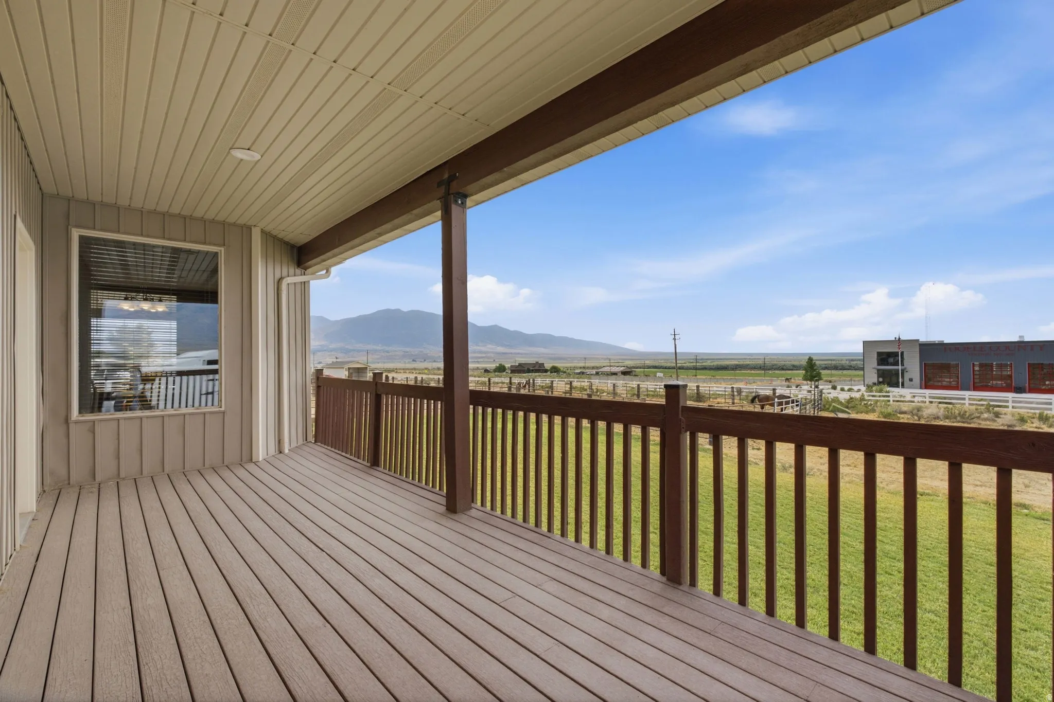 Expansive covered deck featuring wood-finish flooring, a wood railing system, and a recessed ceiling light