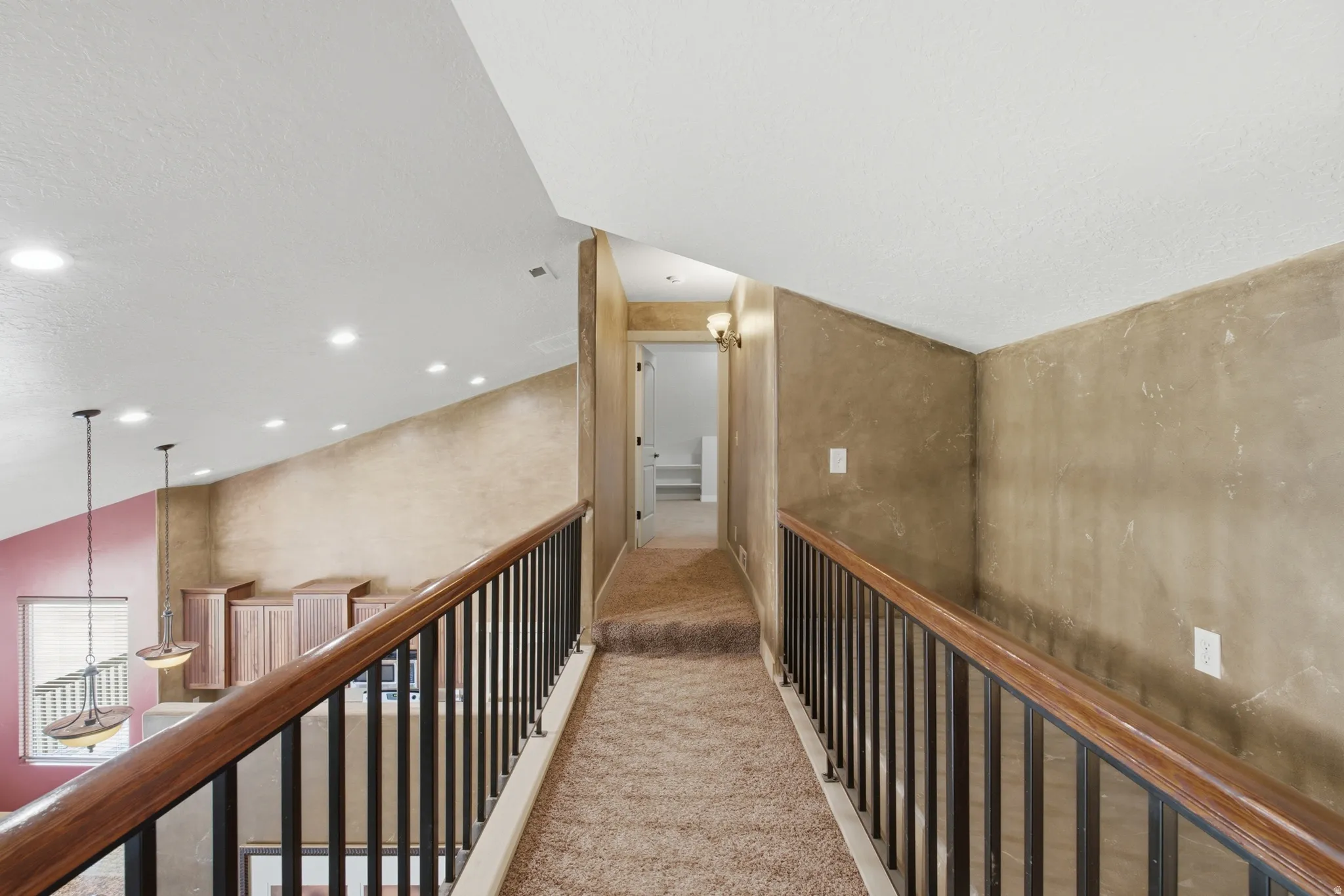 Carpeted hallway with a dark wood and metal railing