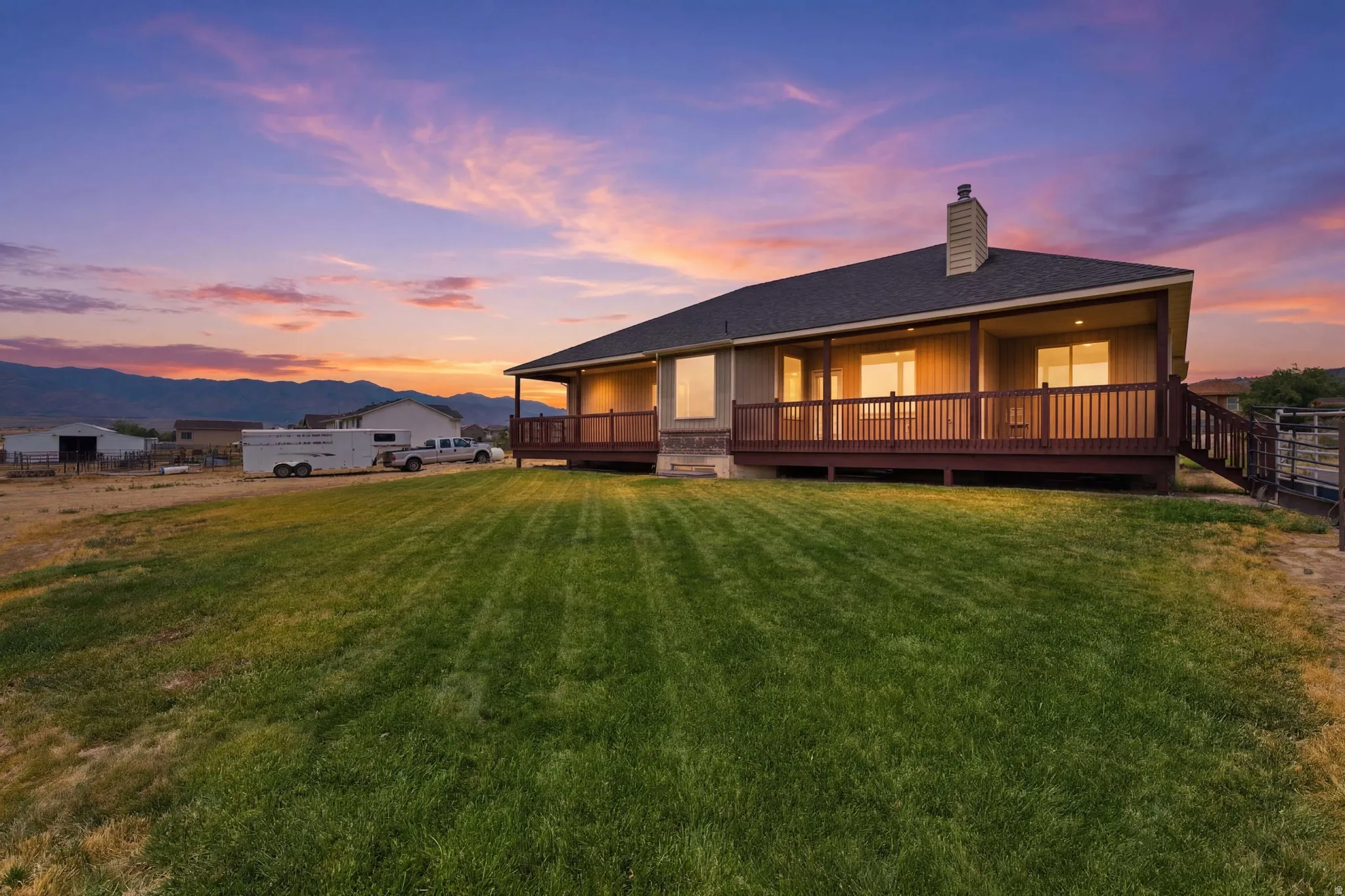 Expansive rear yard featuring a manicured lawn, a full-length covered deck, and a wood railing with stairs